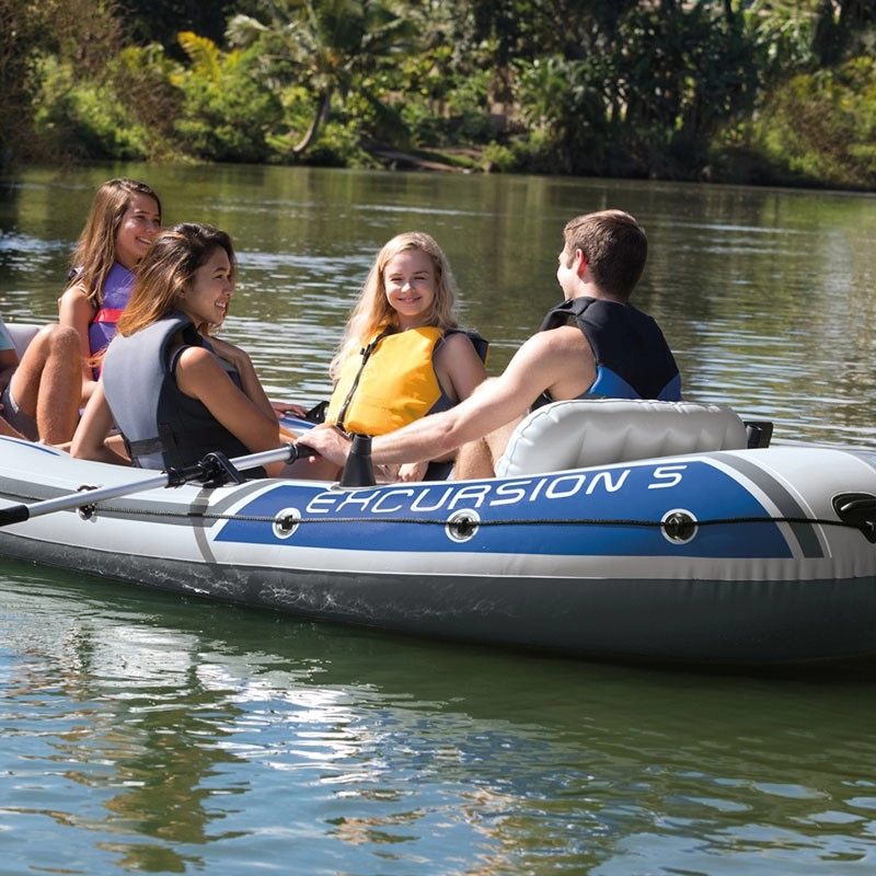 Grupo de jóvenes en bote hinchable gris y azul con remo. 