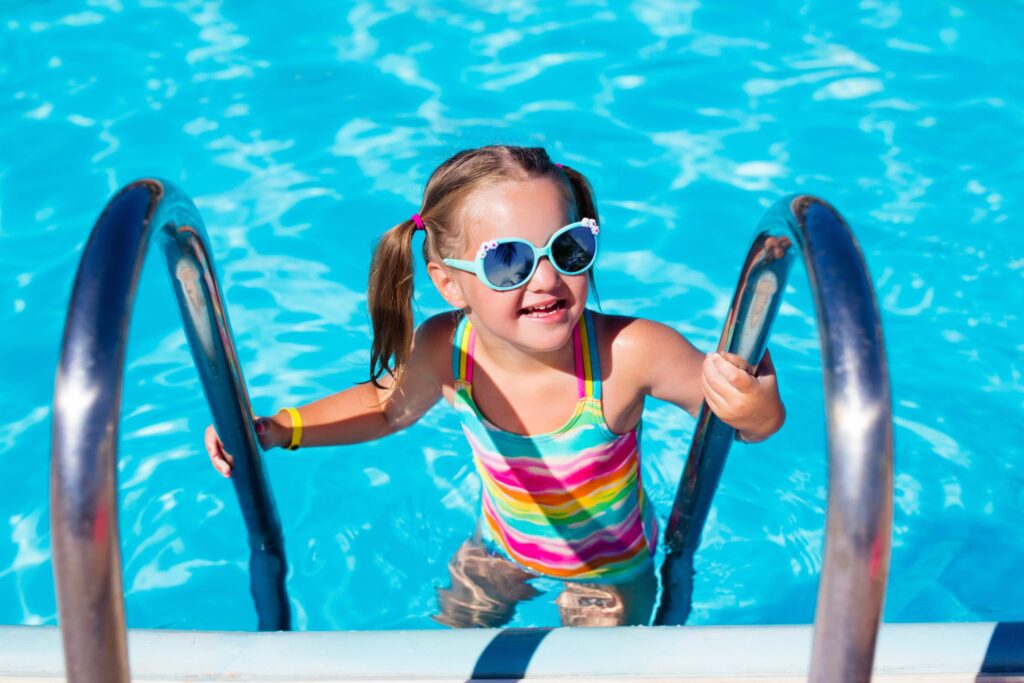 Niña subiendo por escaleras de una piscina 