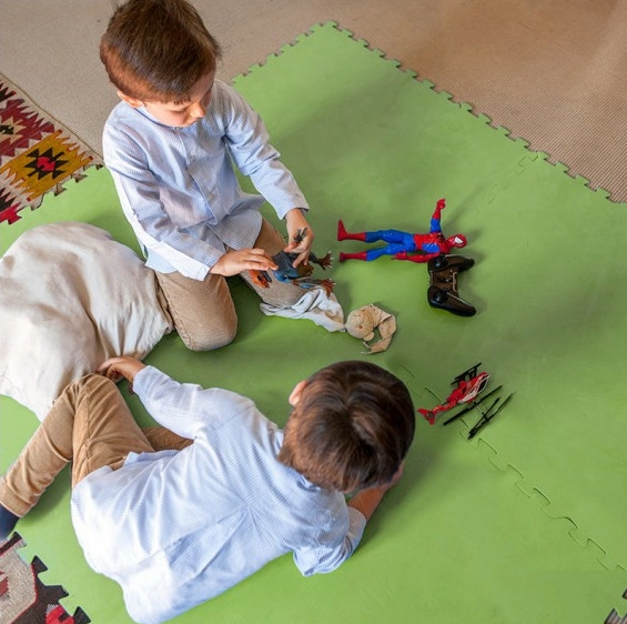 niños jugando sobre suelo de plastico verde